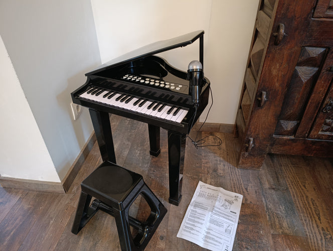 Grand piano sur pied à 37 touches avec microphone, + Tabouret. Nécessite 3 piles AA-non fournies. Fonctionne parfaitement-Quelques griffures sur le couvercles, moins cher chez Petit Kiwi