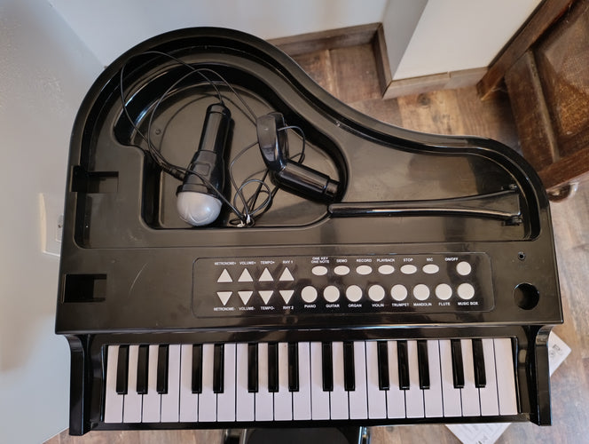 Grand piano sur pied à 37 touches avec microphone, + Tabouret. Nécessite 3 piles AA-non fournies. Fonctionne parfaitement-Quelques griffures sur le couvercles, moins cher chez Petit Kiwi