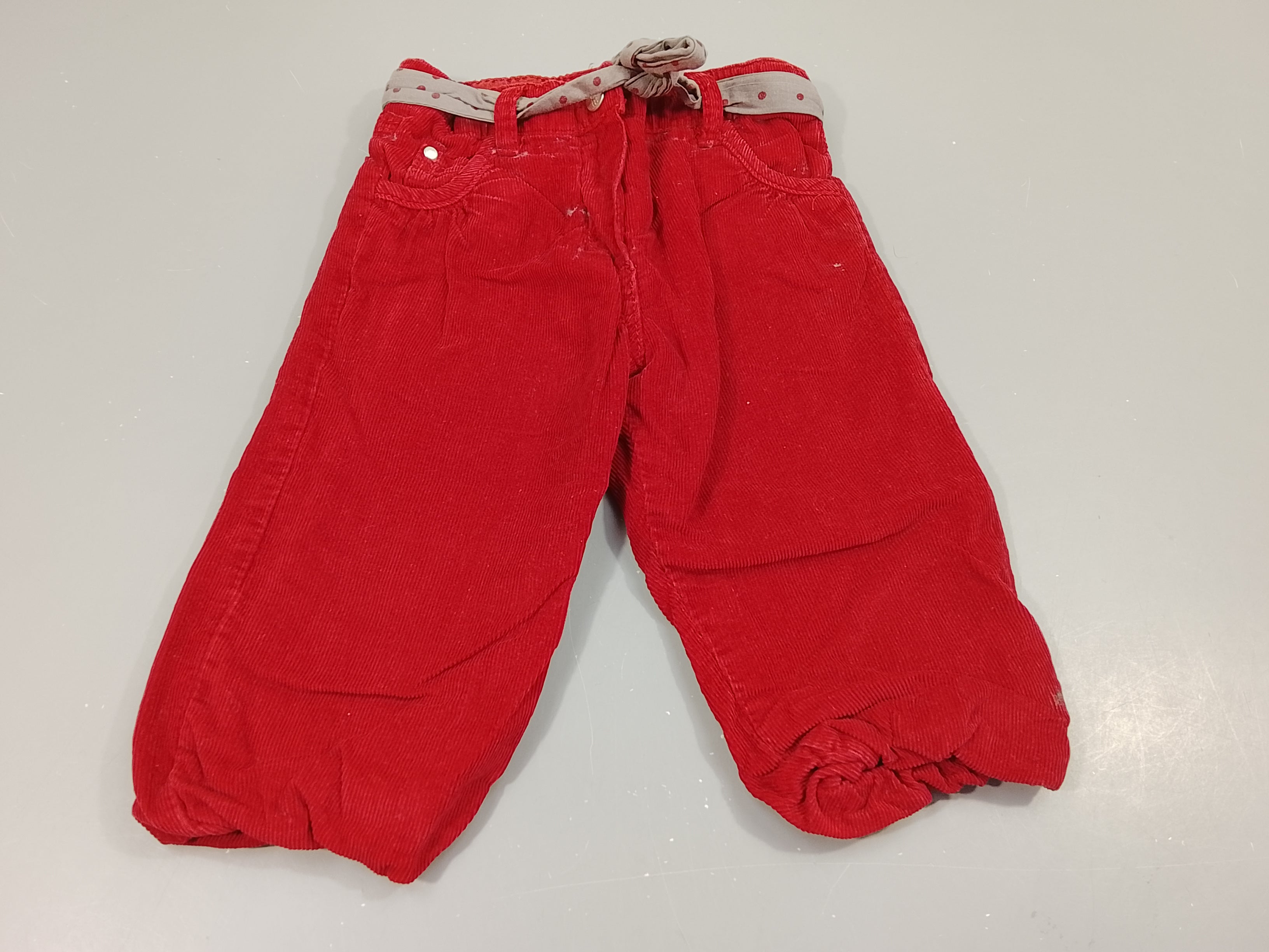 Pantalon velours côtelé rouge, cheville élastique. Ceinture grise à pois rouges