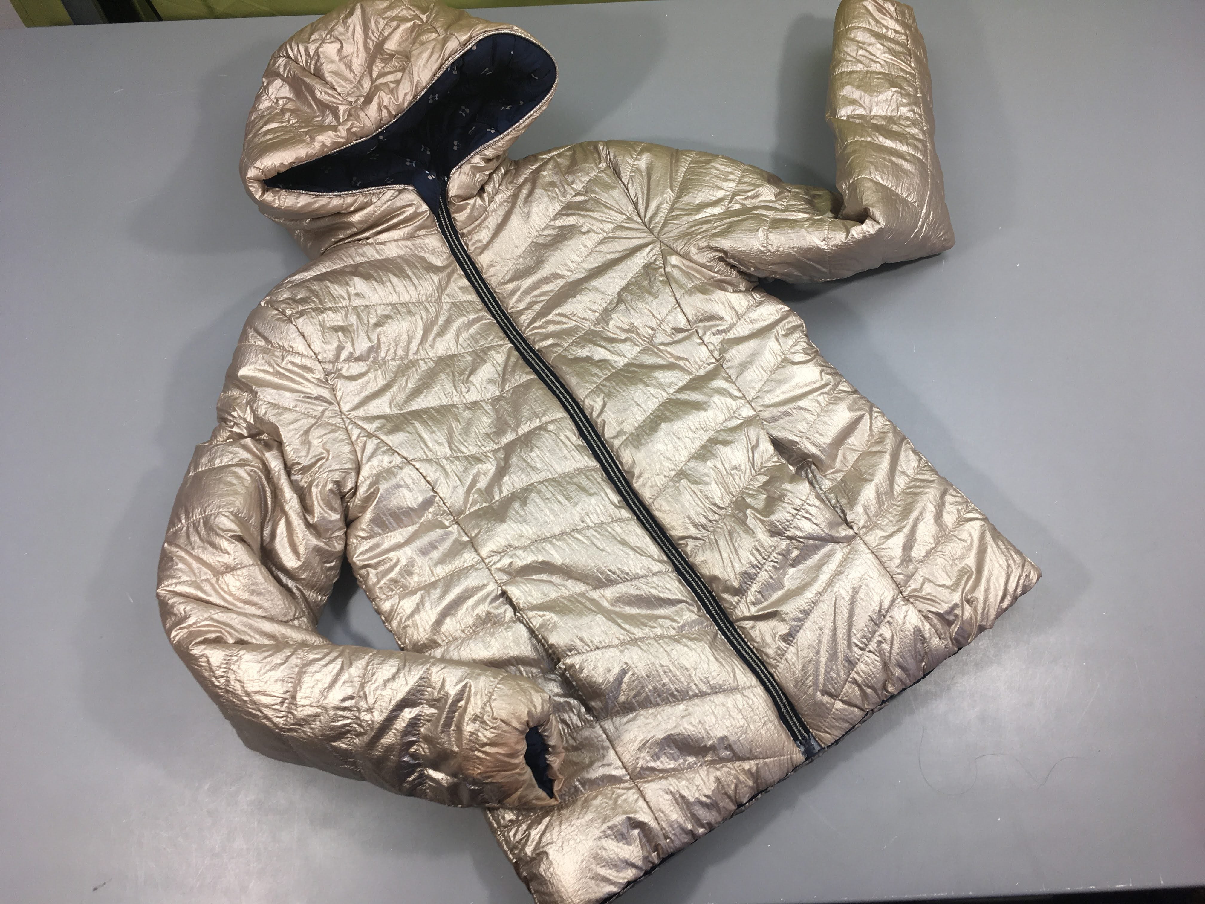 Veste zippée à capuche ouatinée réversible doré/ bleu marine cerise. Bas des manches côté doré légèrement usés