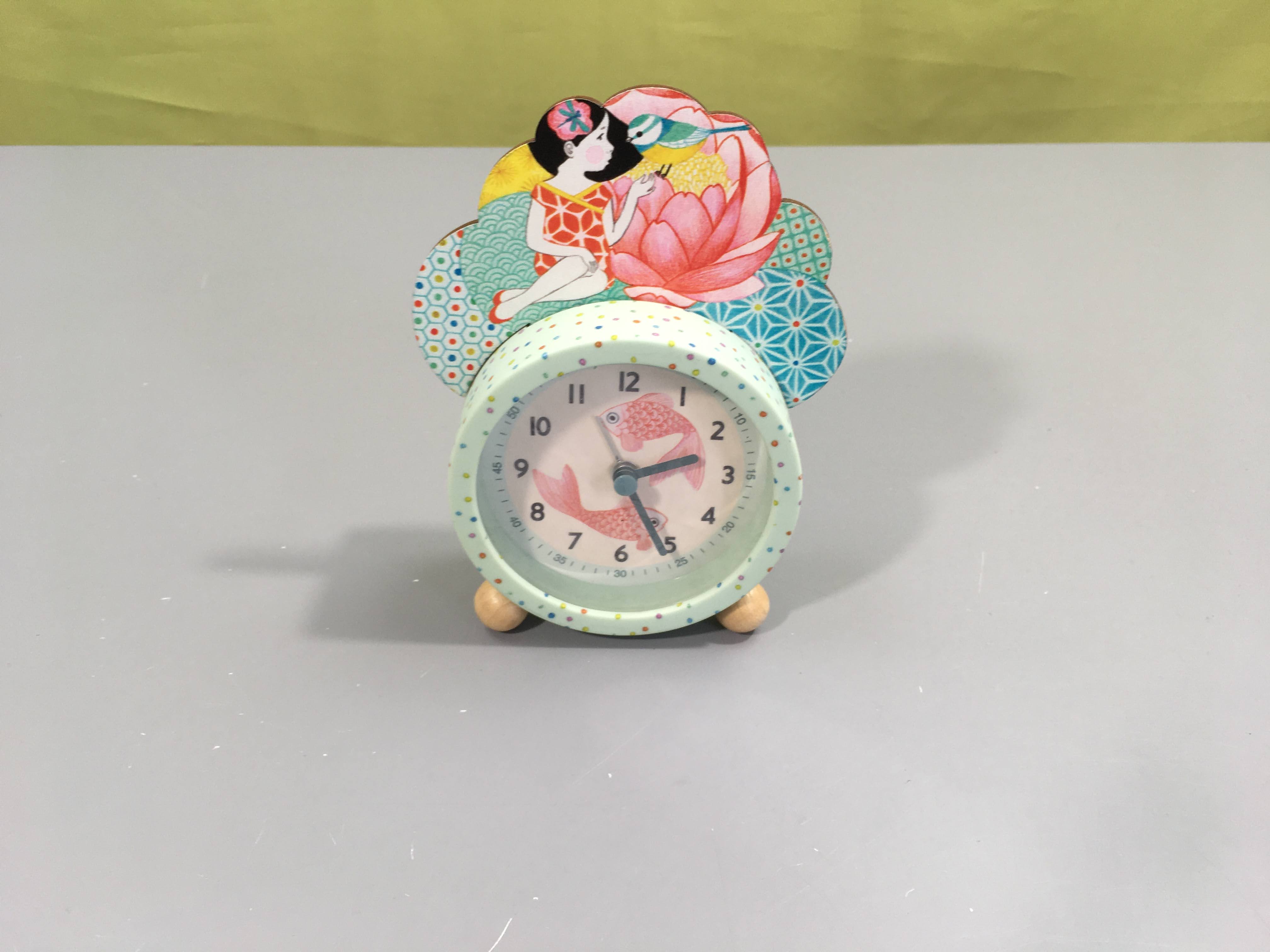 Réveil poisson très coloré est illustré d'une jeune fille assise sur un joli nénuphar.