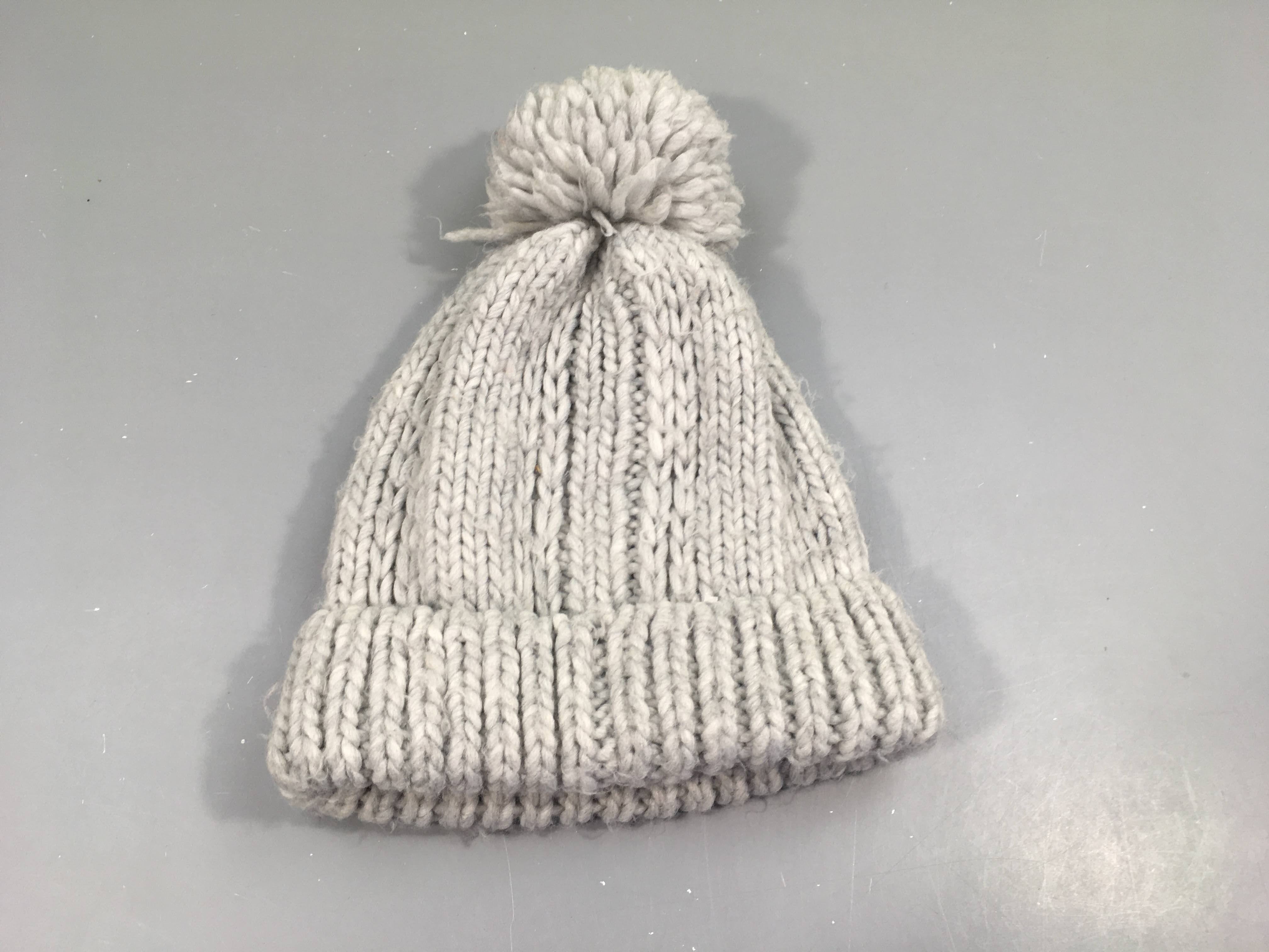 Bonnet tricot gris clair bleuté,pompon . Un peu bouloché