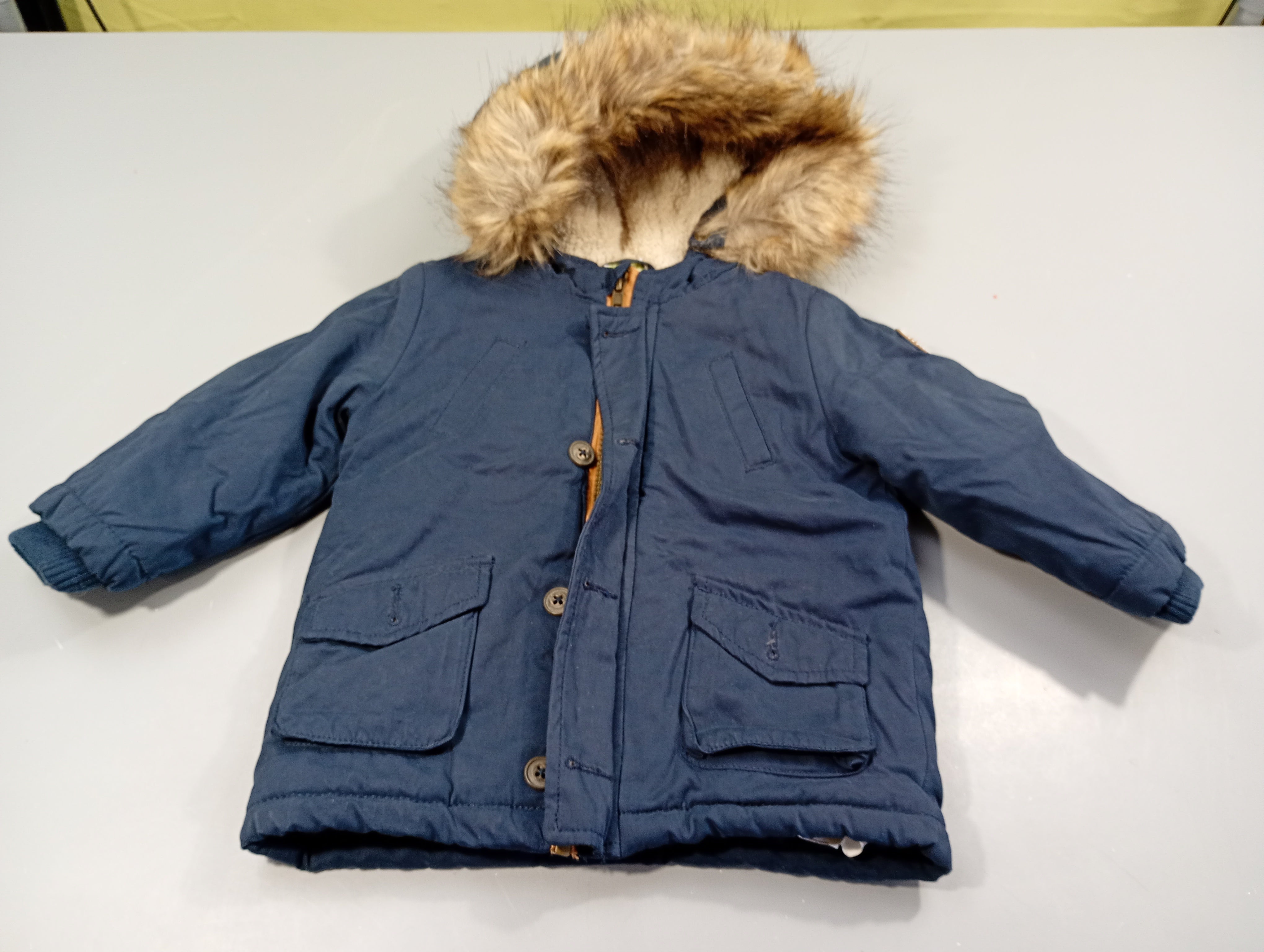 Manteau bleu marine  zippé à capuche avec fausse fourrure, manque 1 bouton. Intérieur peluche