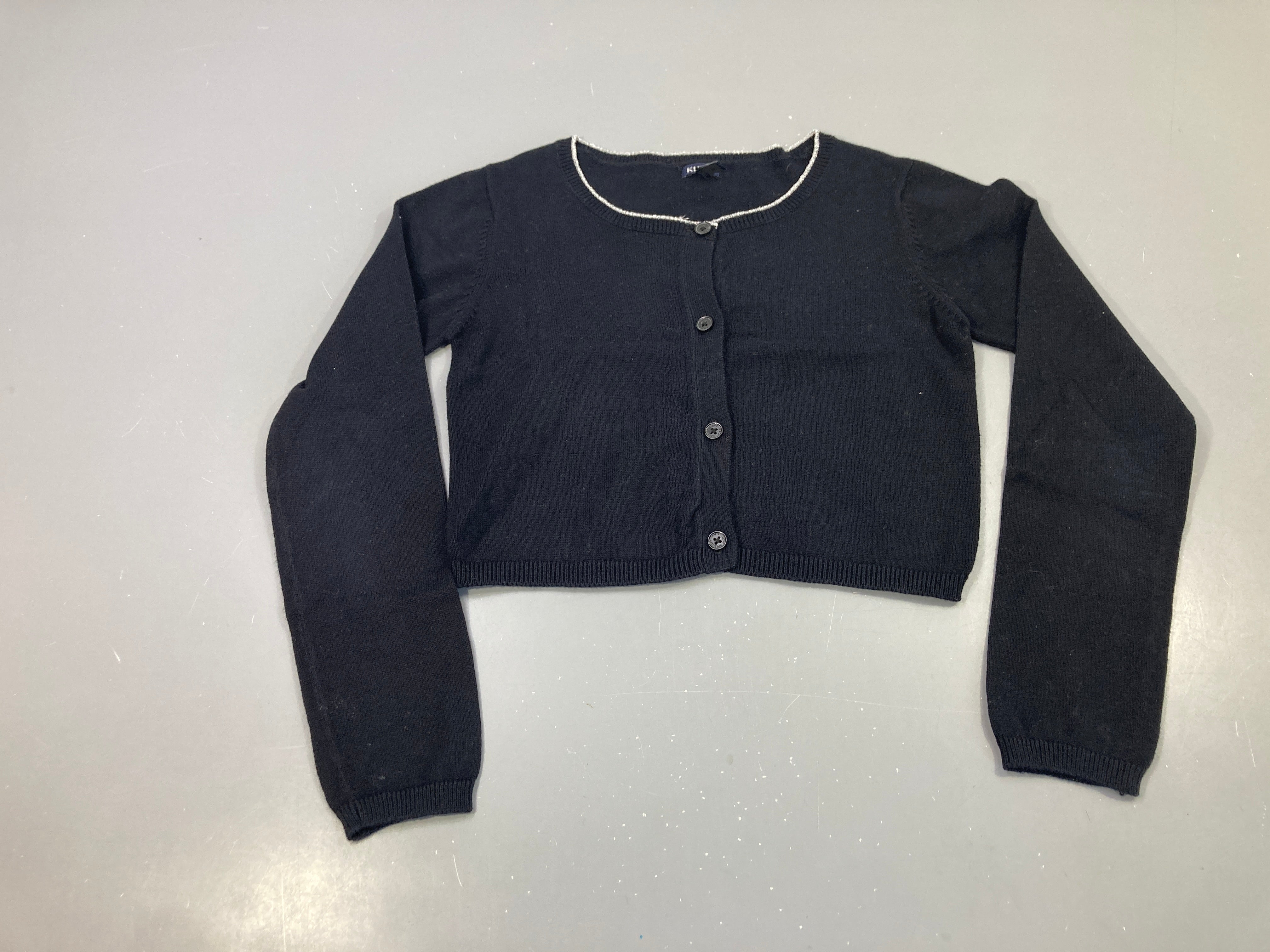 Gilet court noir, liseré pailleté au col, boutons