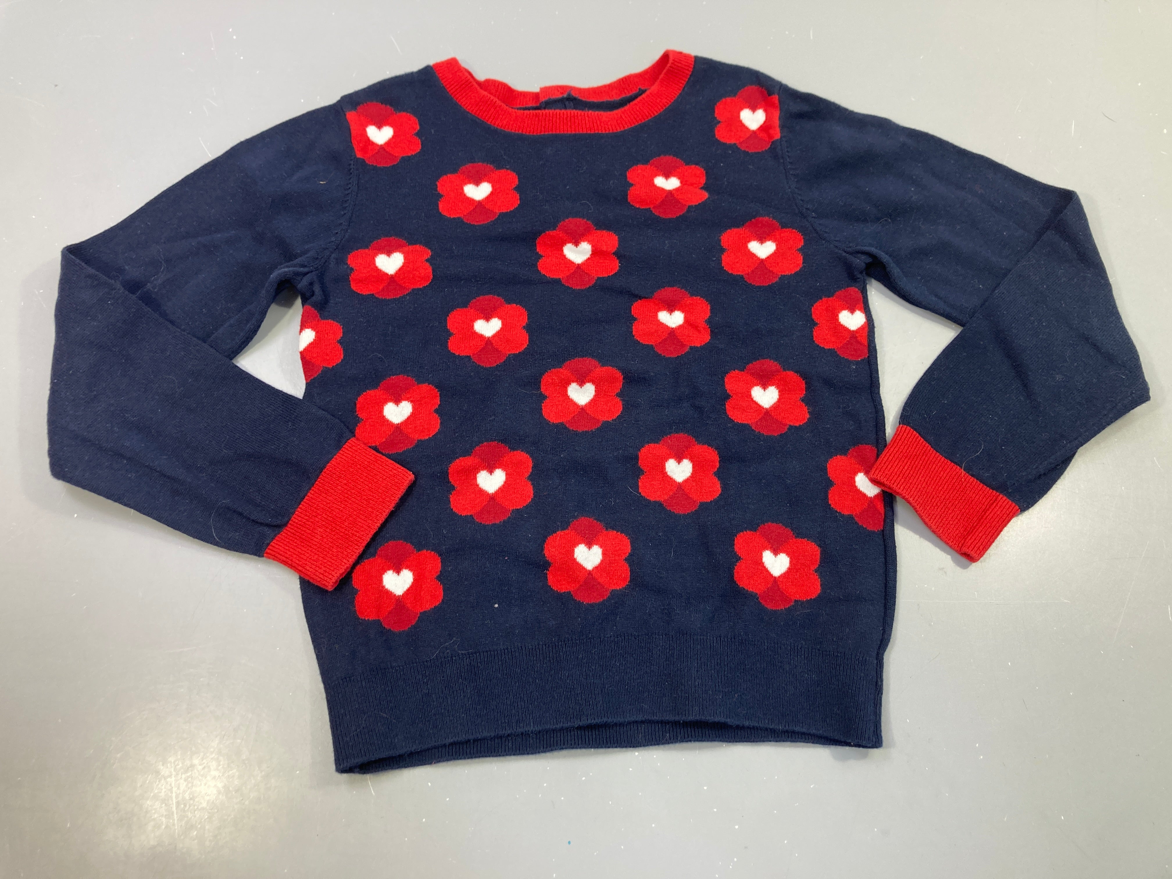 Pull bleu marine à fleurs rouge et blanc, très légèrement bouloché