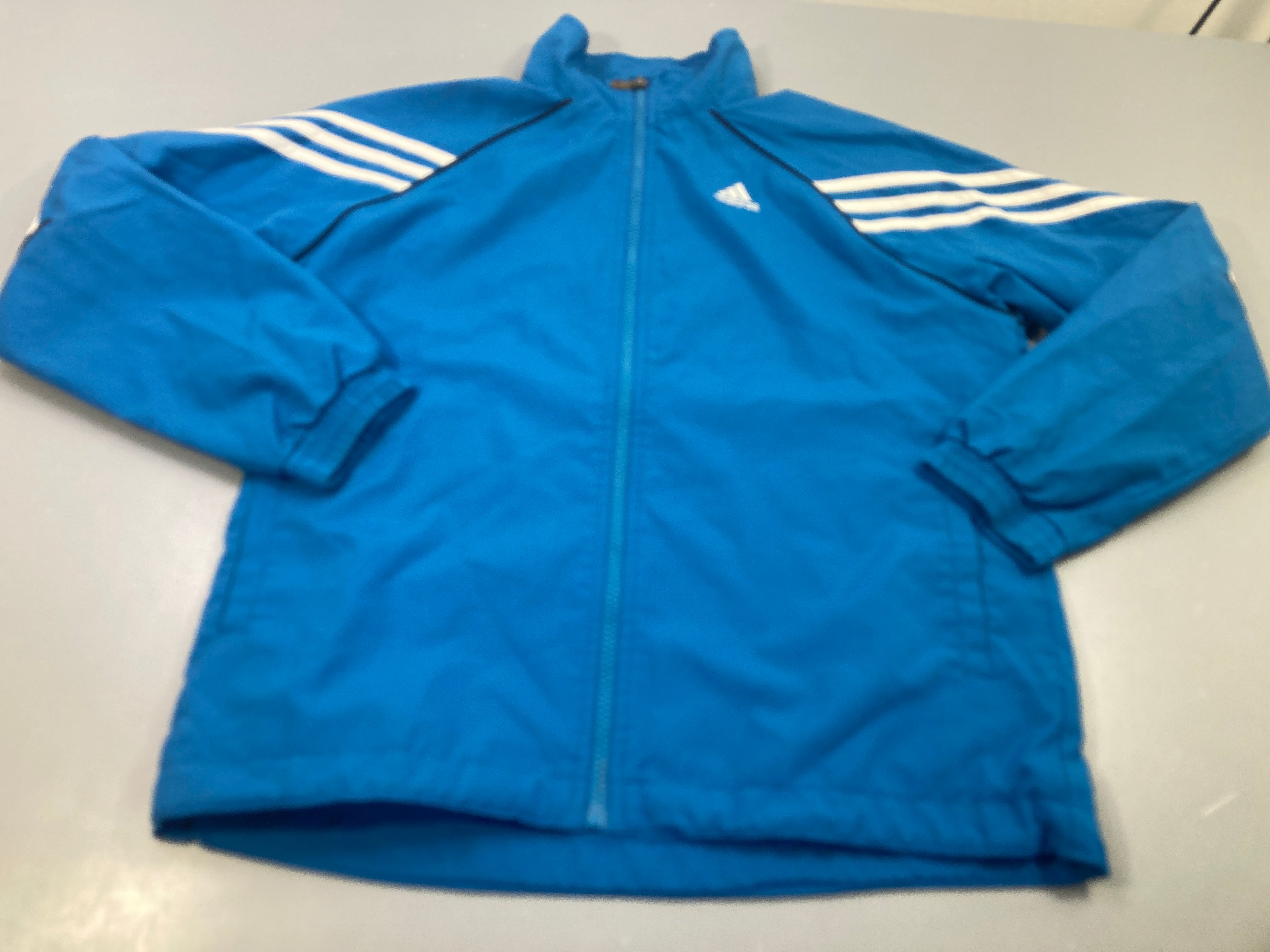 Survêtemnt de sport zippé bleu et blanc, petite tache au niveau du zip