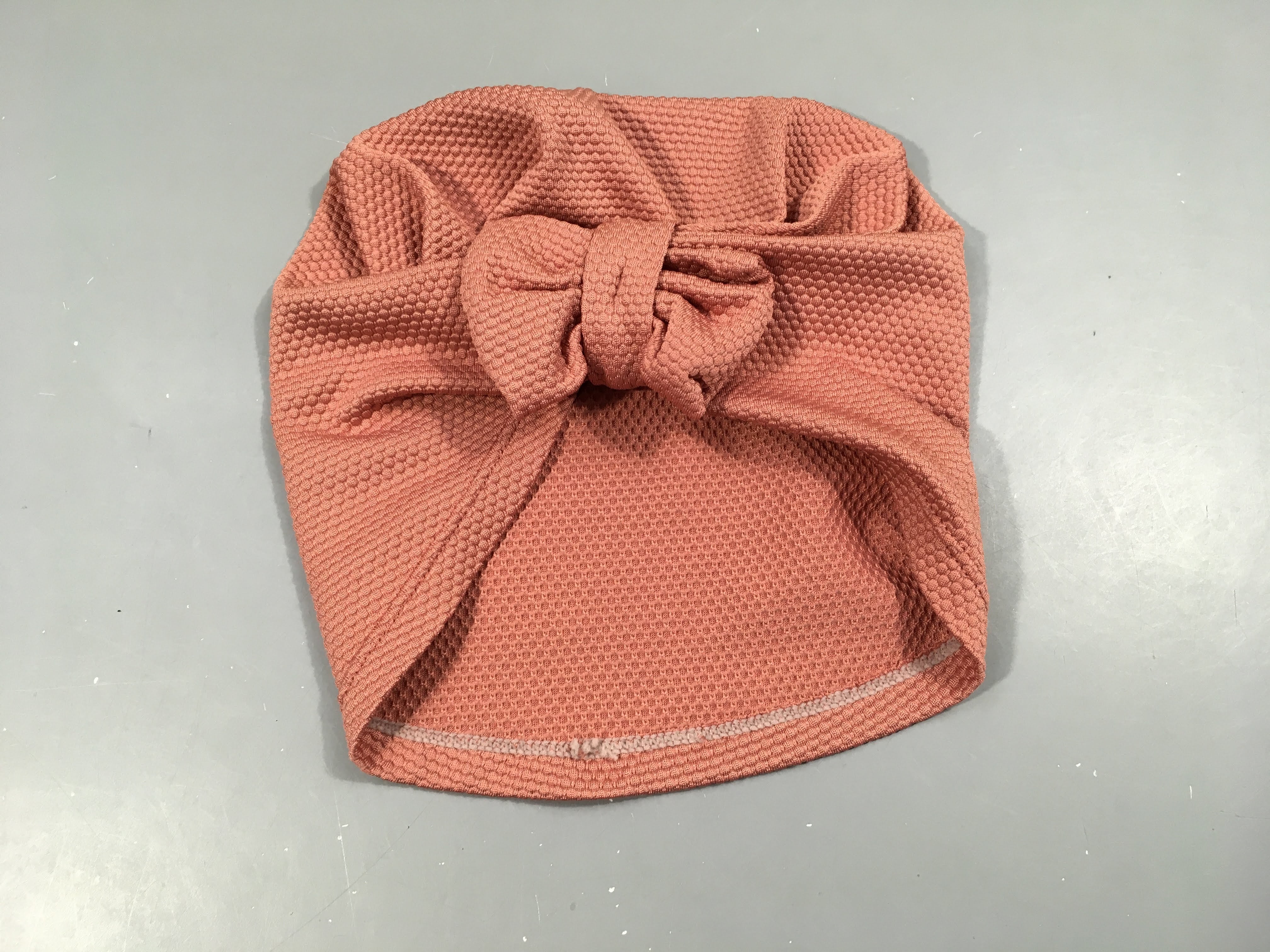 Bonnet de bain, vieux rose texturé avec noeud. Prot.ection 50+, pas de taille indiqué, estimée 50cm
