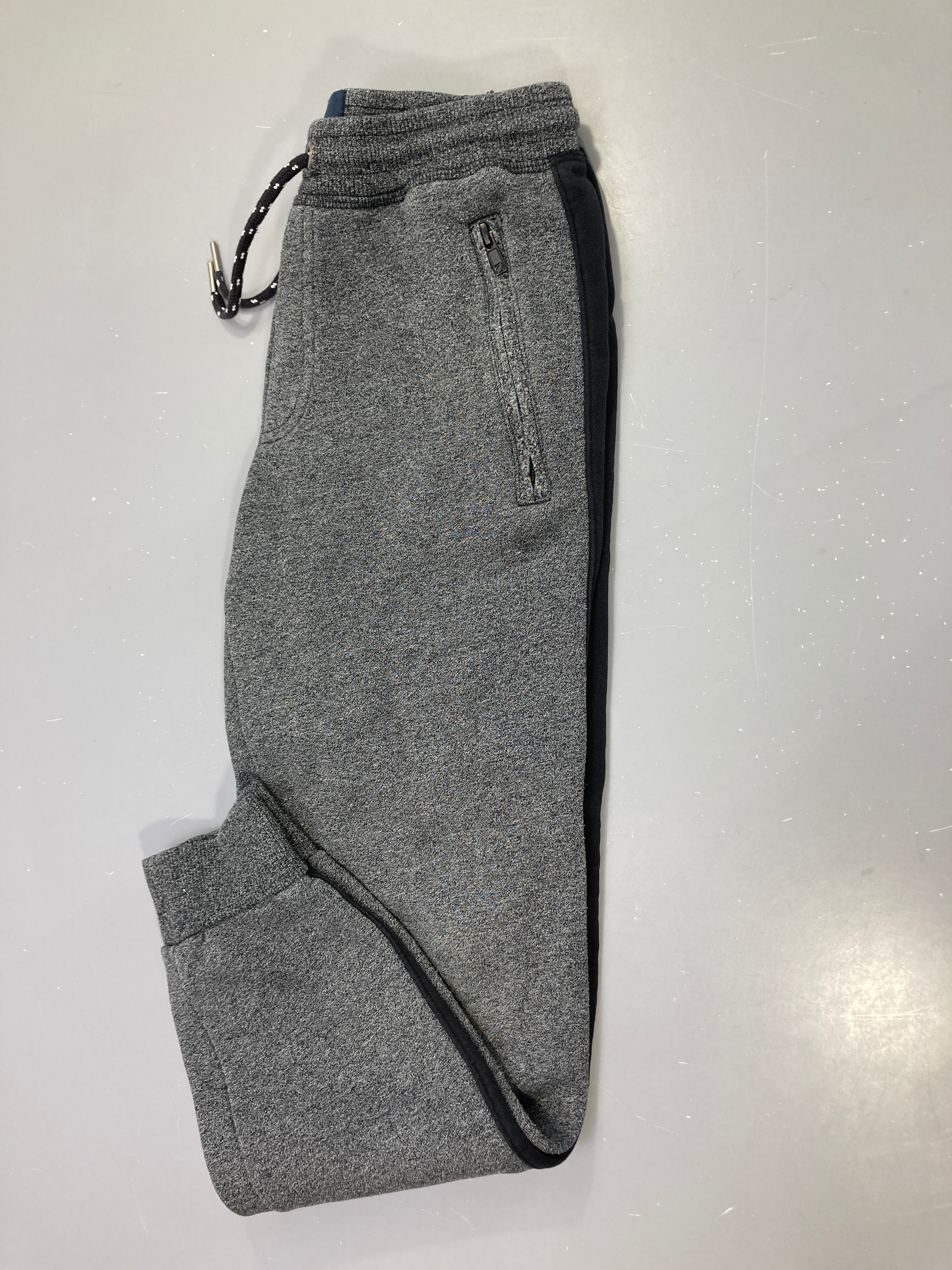 Jogging gris chiné bandes noires, poches zippées, molleton un peu bouloché
