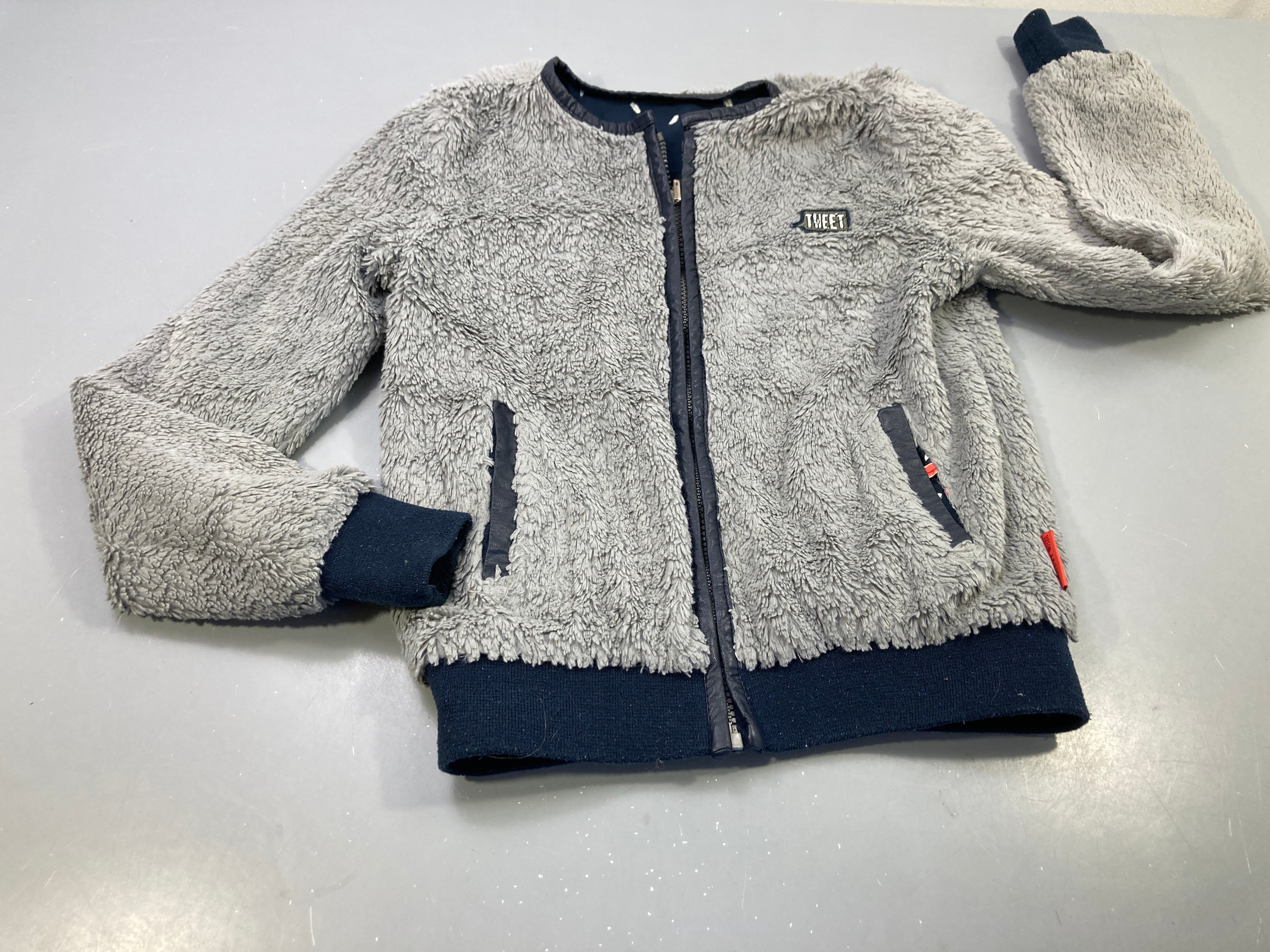 Gilet zippé réversible  bleu marine feuilles blanches/ peluche gris légèrement bouloché,  pas de taille indiquée, estimée 6a
