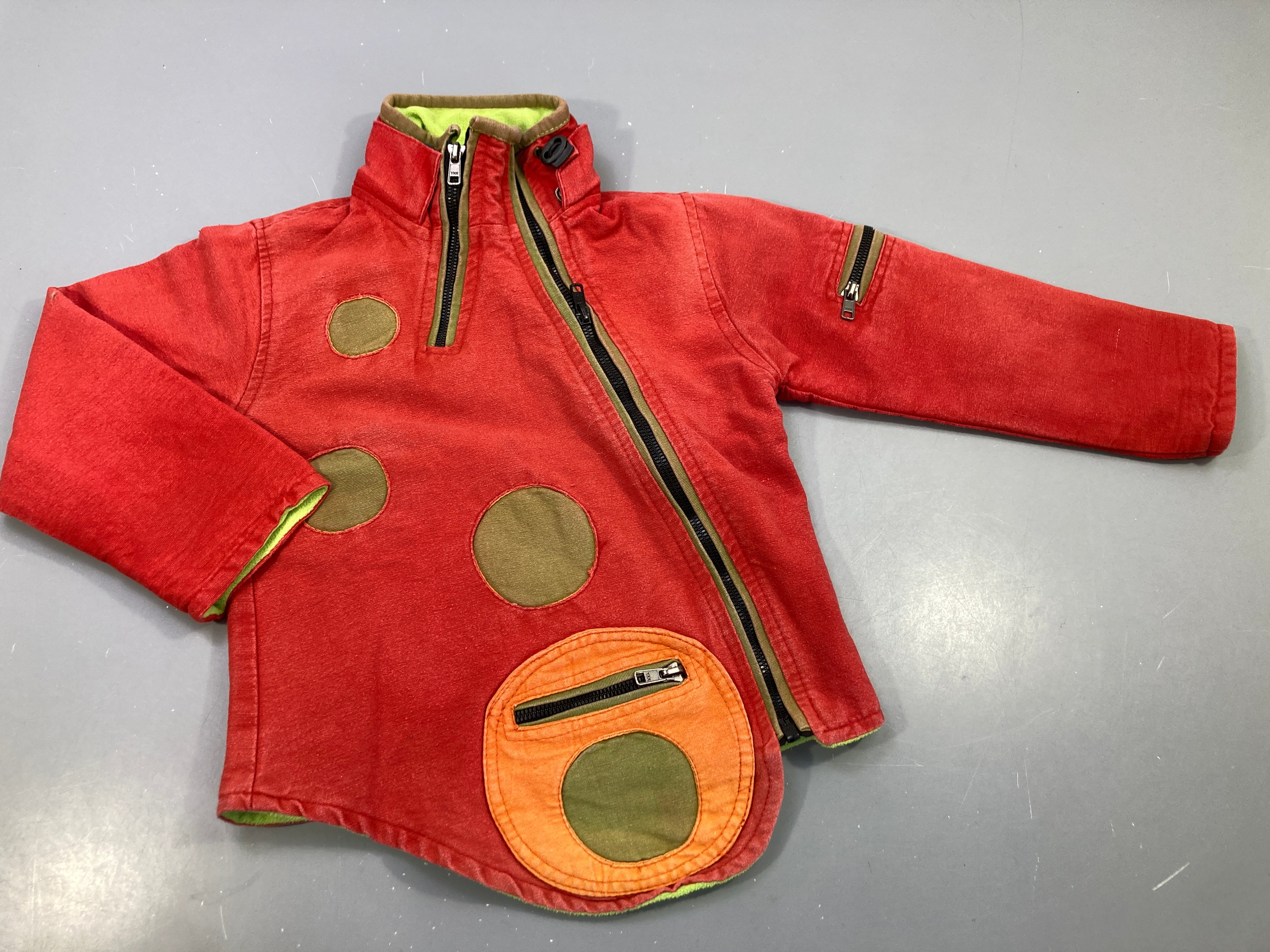 Veste zippée asymétrique rouge , motifs rond colorés, intérieur polar. Akamandu. T2
