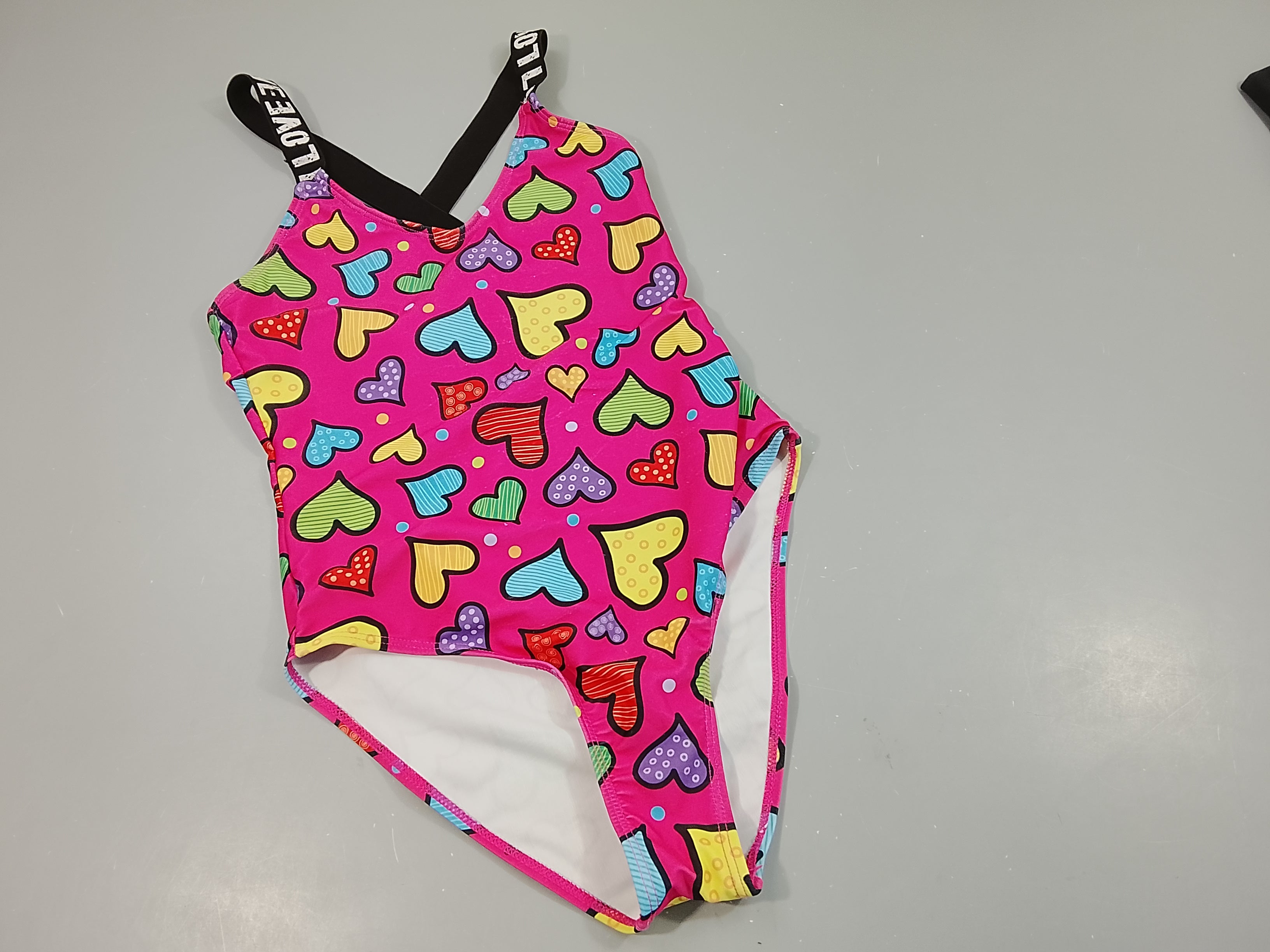 Maillot rose, motifs coeurs colorés, bretelles noires inscriptions blanches.  Pas de taille indiquée ,estimée 14a