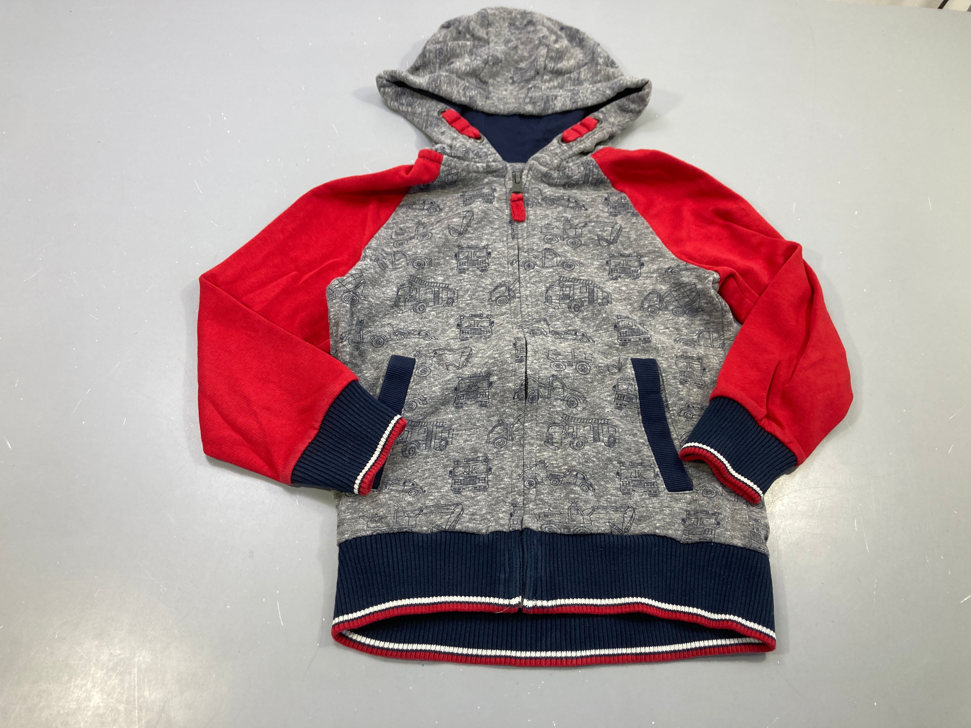 Sweat zippé à capuche gris chiné,motifs véhicules, manches rouges. Légèrement bouloché