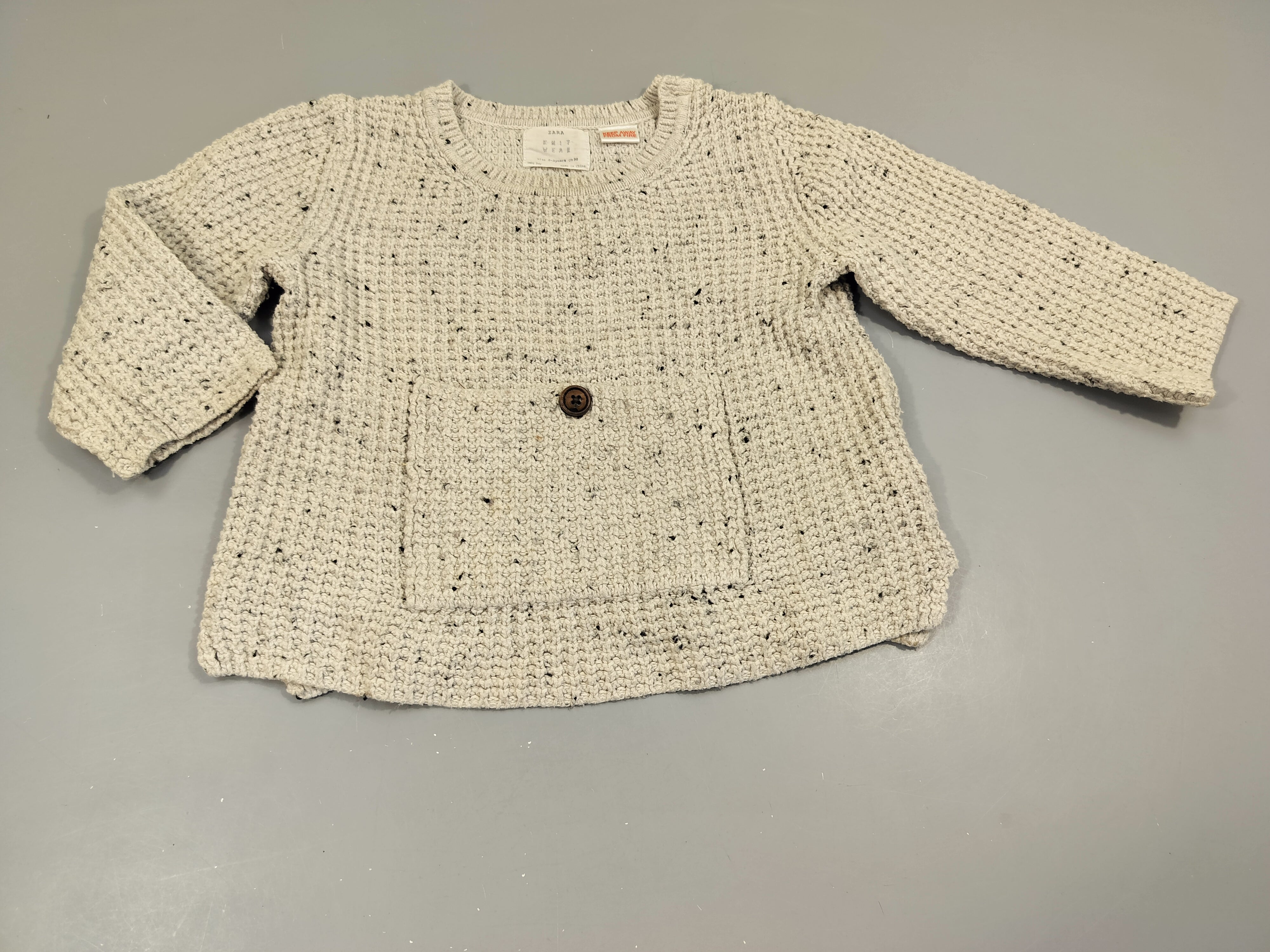 Pull style crochet gris clair moucheté noir , poche à l'avant. Tâché , à relaver